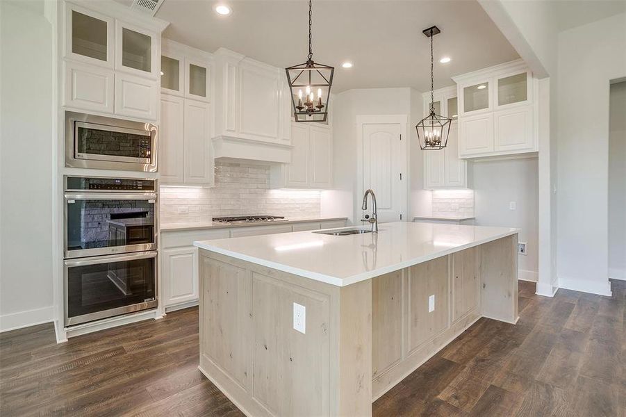 Kitchen featuring a kitchen island with sink, white cabinets, sink, dark hardwood / wood-style flooring, and stainless steel appliances