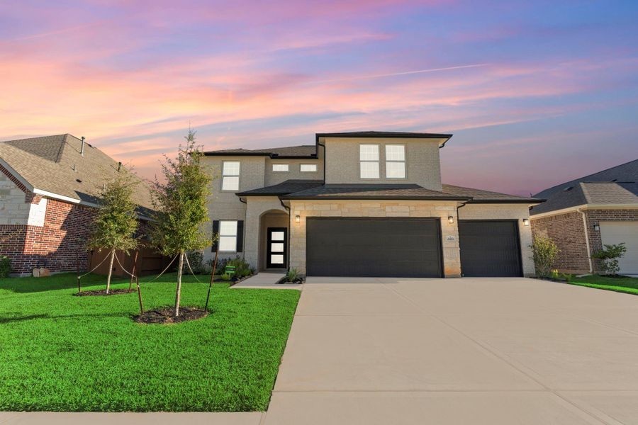 A stunning dusk view of the San Marcos Floor Plan by CastleRock Communities highlights the home’s elegant brick-and-stone exterior, spacious three-car garage, and manicured landscaping—an inviting sight as the evening glow sets the perfect mood.