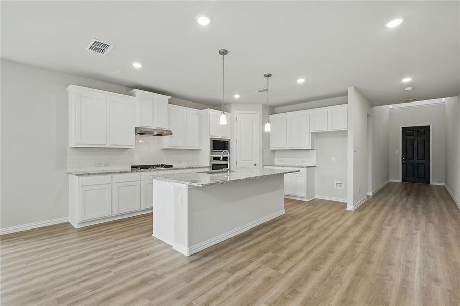 Kitchen with under cabinet range hood, stainless steel appliances, light wood-type flooring, decorative backsplash, and recessed lighting Kitchen with under cabinet range hood, stainless steel appliances, light wood-type flooring, decorative backsplash, and recessed lighting