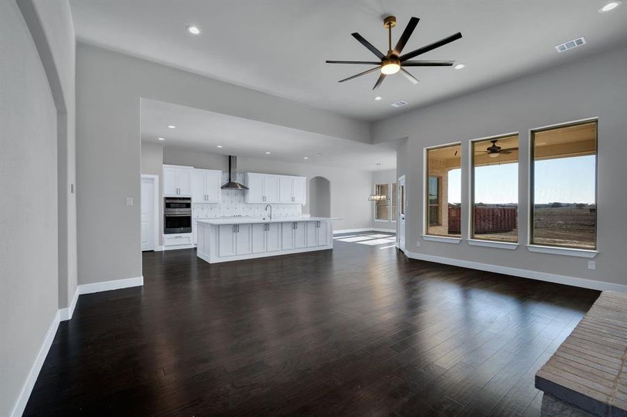 Unfurnished living room featuring sink, dark wood-type flooring, and ceiling fan