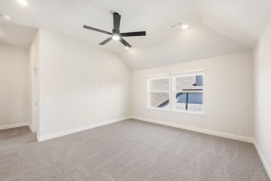Empty bedroom with vaulted ceiling, black ceiling fan, carpet flooring, and a single window