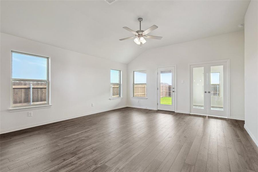 Empty room with dark hardwood / wood-style flooring, ceiling fan, and plenty of natural light