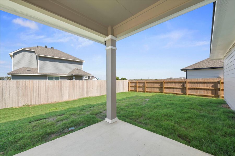 A spacious covered patio overlooks a private, fenced backyard, ideal for outdoor gatherings.