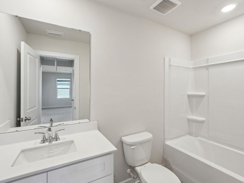 The secondary bathroom features an oversized tub shower for guests.