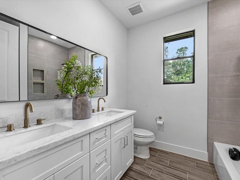 secondary/guest bathroom located on the first floor, features double sinks and lovely gold finishes