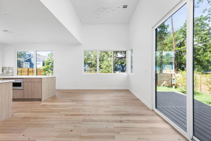Unfurnished dining area featuring track lighting, light wood-type flooring, and baseboards