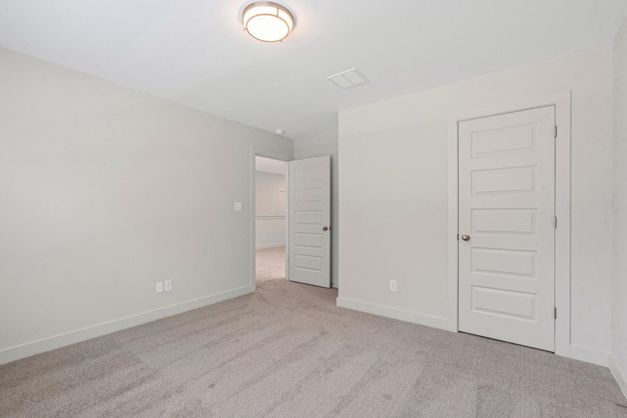 Spacious room featuring neutral carpeting, light gray wall paint, and white baseboards Spacious room featuring neutral carpeting, light gray wall paint, and white baseboards