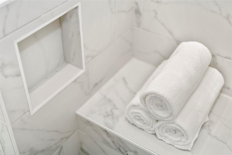 Bench seat and extra niche located in primary bathroom shower for a luxurious touch