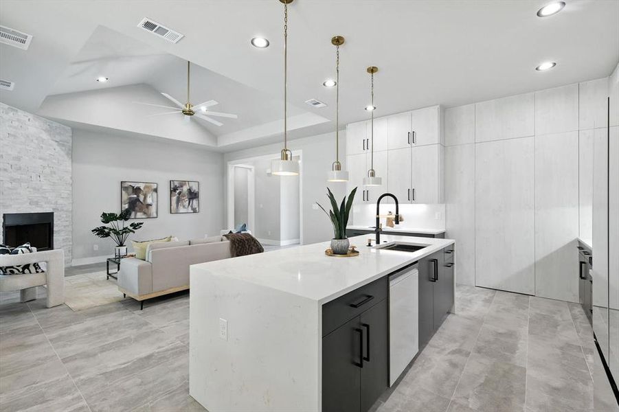 Kitchen with open floor plan, decorative light fixtures, modern cabinets, an island with sink, and ceiling fan