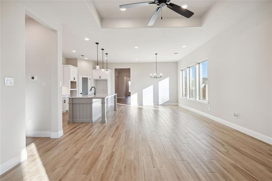 Unfurnished living room featuring ceiling fan with notable chandelier and sink