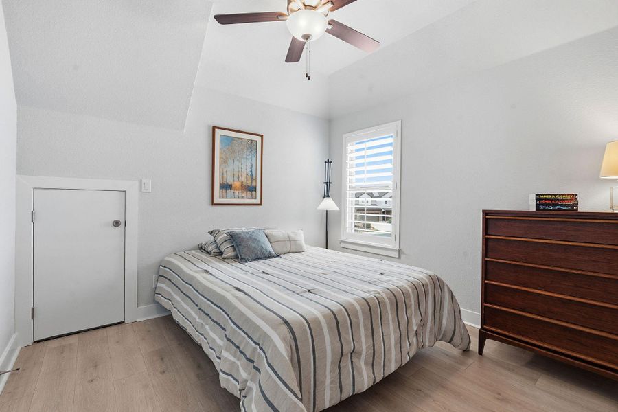 Bedroom with light wood-style flooring, a ceiling fan, and vaulted ceiling
