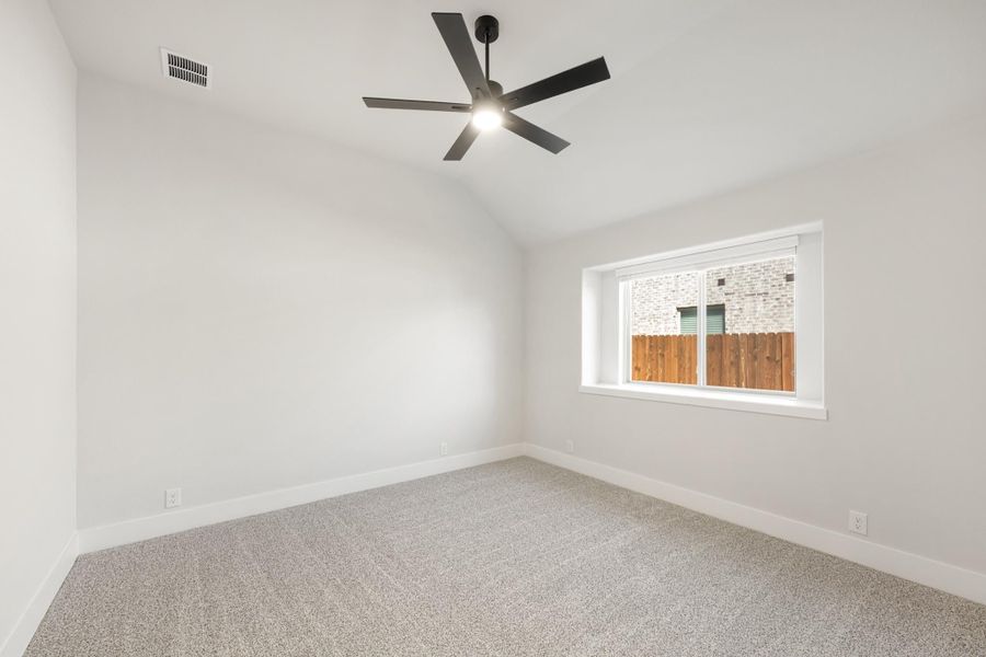 Empty bedroom with vaulted ceiling, black ceiling fan, carpet flooring, and single window