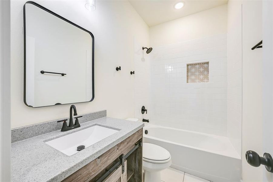 Bathroom featuring a white subway tile shower surround with a decorative niche, a white tub, and matte black fixtures Bathroom featuring a white subway tile shower surround with a decorative niche, a white tub, and matte black fixtures