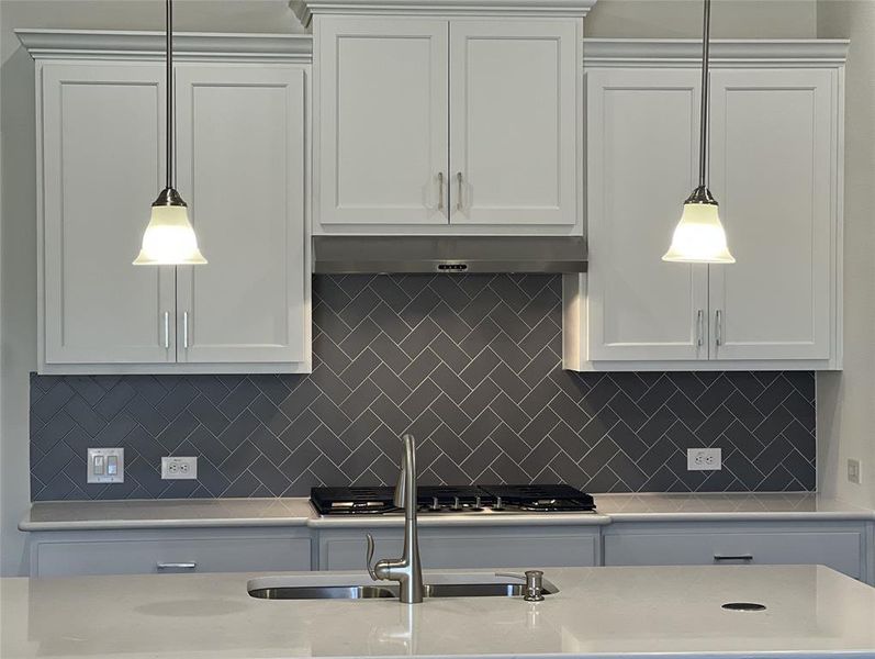 Kitchen featuring backsplash, decorative light fixtures, and range hood