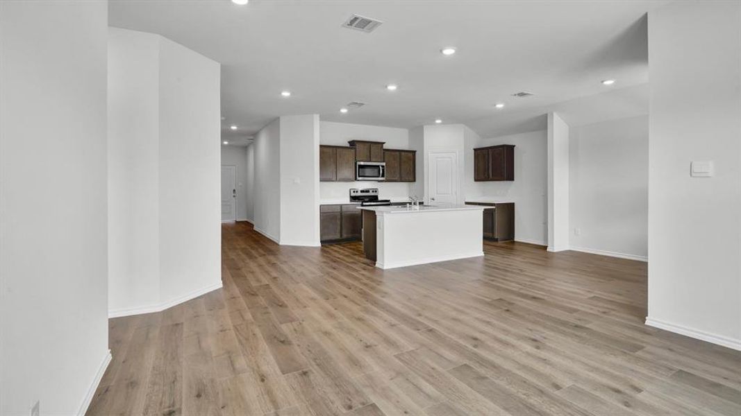 Kitchen with a kitchen island with sink, light wood-type flooring, open floor plan, recessed lighting, and stainless steel appliances