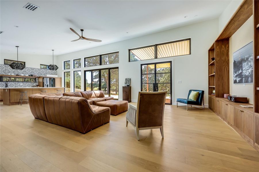 Living area with light wood finished floors and ceiling fan