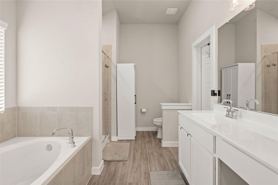 The spa-inspired primary bathroom offers a bright and modern retreat featuring a large walk-in shower with an upgraded oversized rain shower head for a luxurious experience. Relax in the soaking tub surrounded by elegant tile accents, perfect for unwinding after a long day. The spacious vanity provides ample counter space and storage with sleek contemporary finishes. High ceilings and neutral tones enhance the open, airy feel, while the generously sized walk-in closet offers excellent storage.
