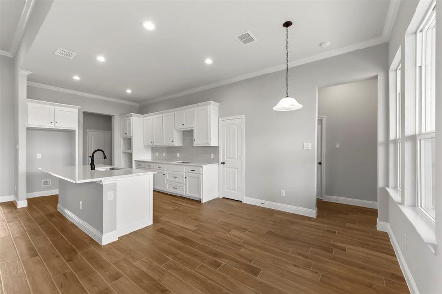 Kitchen with a center island with sink, decorative light fixtures, white cabinetry, and sink