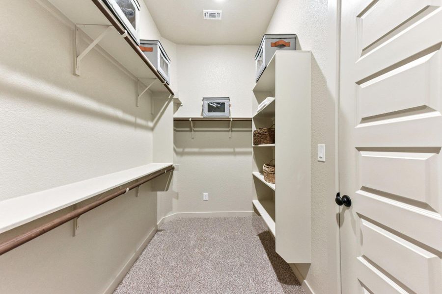 A well-organized walk-in closet provides abundant storage with carpeted floors and accessible shelving. A well-organized walk-in closet provides abundant storage with carpeted floors and accessible shelving.