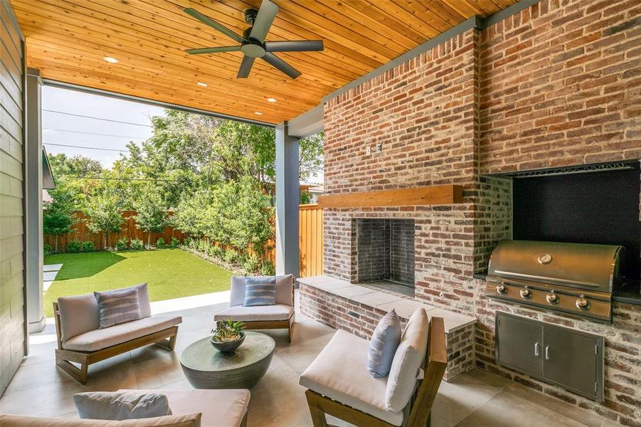 View of patio with exterior kitchen, an outdoor living space with a fireplace, ceiling fan, and grilling area