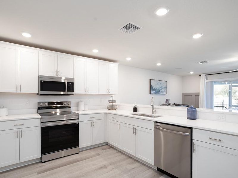 The large kitchen includes ample cabinet and counter space, a pantry, and breakfast bar - Azalea townhome by Highland Homes