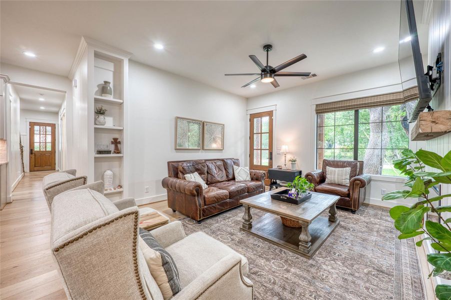Spacious living area featuring light wood-finish flooring, recessed lighting, a ceiling fan, and built-in shelving