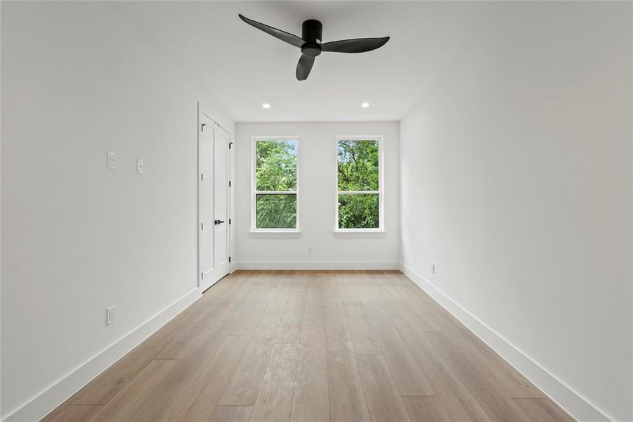 Empty room with a ceiling fan, light wood finished floors, and recessed lighting