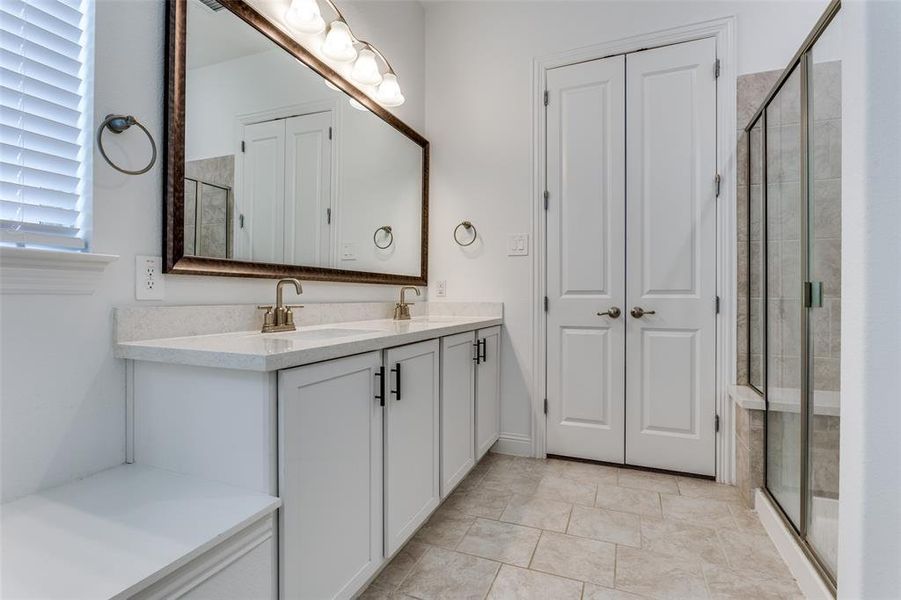 Primary Bathroom ensuite to primary bedroom, featuring tile patterned floors, double sink vanity, and an enclosed oversized shower