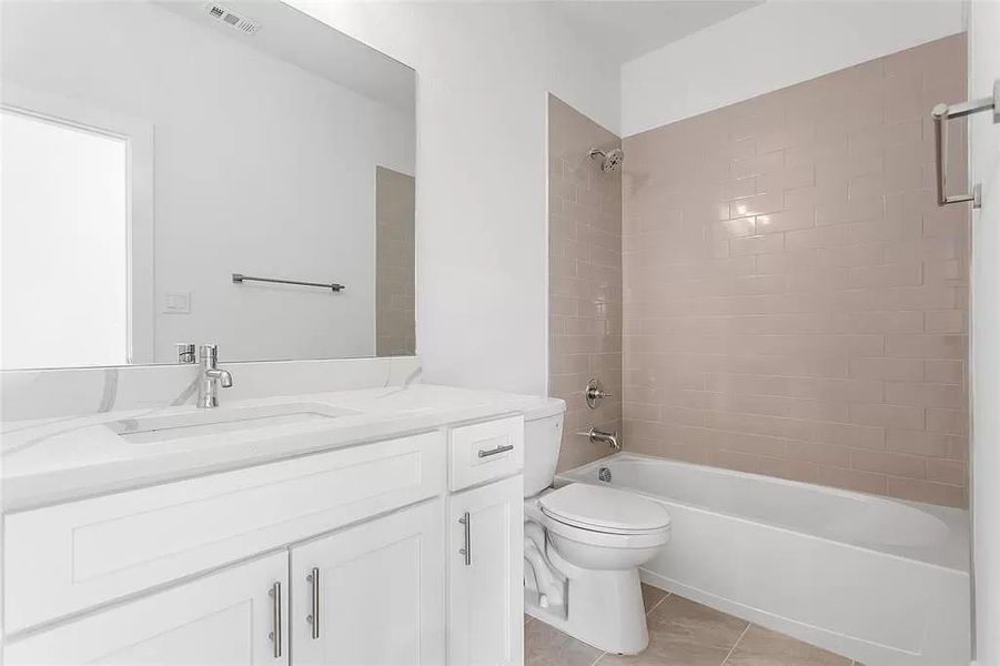 Full bathroom featuring vanity, tiled shower / bath, tile patterned flooring, and toilet