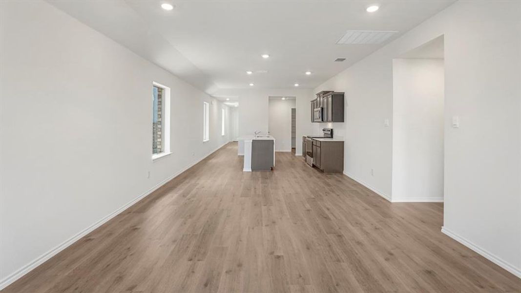 Open-concept living area with wood-finish flooring, recessed lighting, and white baseboards