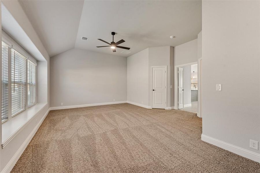 Empty room with light colored carpet, lofted ceiling, and ceiling fan Empty room with light colored carpet, lofted ceiling, and ceiling fan