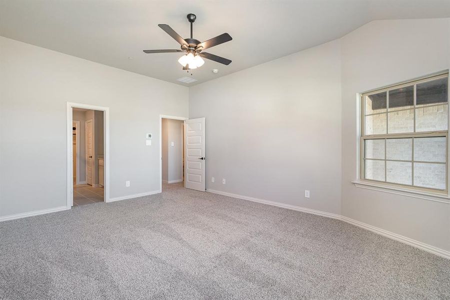 Unfurnished bedroom with ceiling fan, lofted ceiling, and light colored carpet