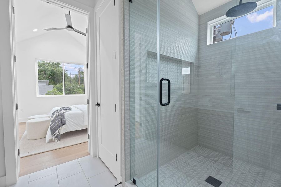 Ensuite bathroom featuring tile patterned floors, a stall shower, vaulted ceiling, and ceiling fan