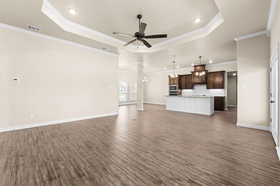 Unfurnished living room, a raised ceiling, crown molding, recessed lighting, and a ceiling fan Unfurnished living room, a raised ceiling, crown molding, recessed lighting, and a ceiling fan