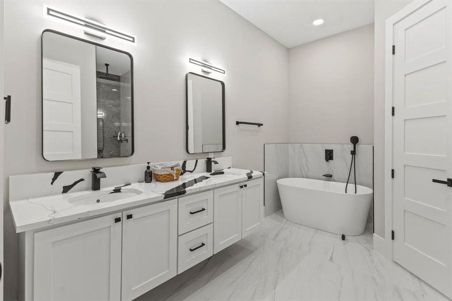 Bathroom with double vanity, a freestanding bath, a shower stall, light marble finish flooring, and recessed lighting