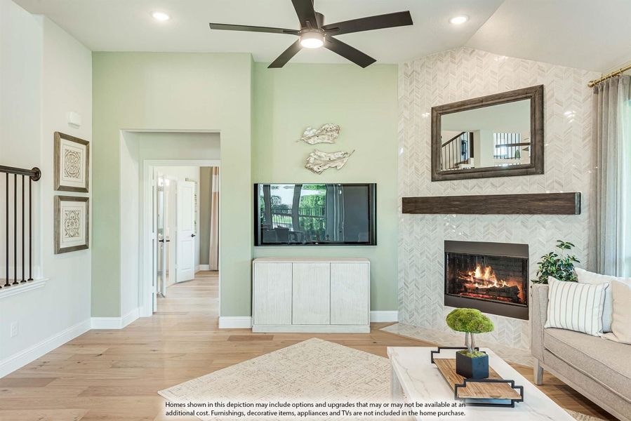 Living room with herringbone tile fireplace, hardwood floors, ceiling fan, and high ceilings