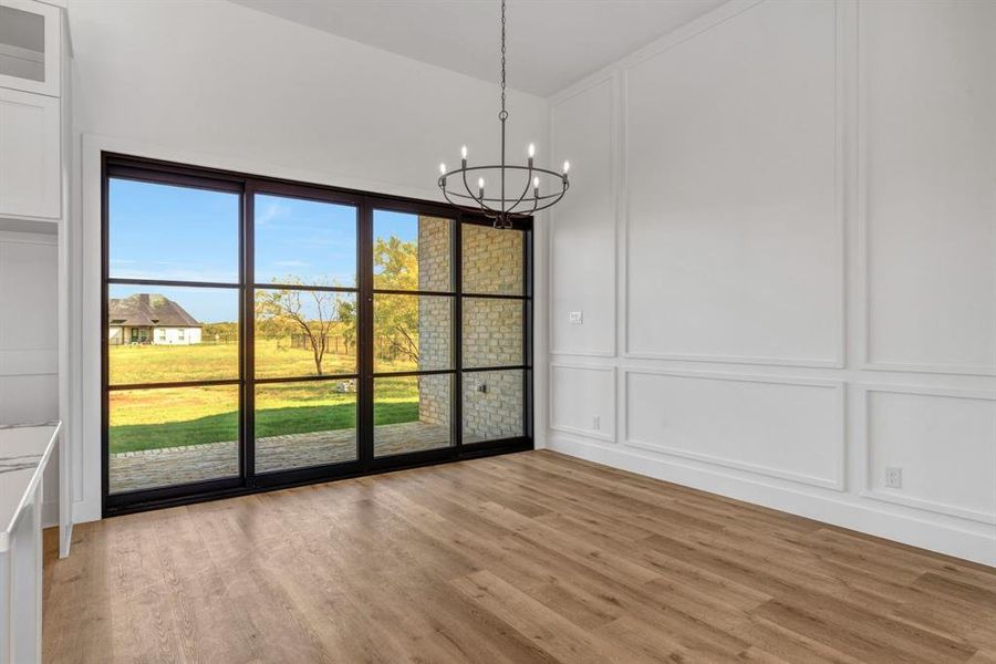 Dining area featuring a decorative wall, light wood-type flooring, and a chandelier