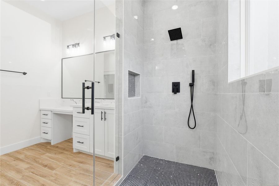 The en-suite bath offers a dedicated vanity area, and a luxurious glass-enclosed shower equipped with soap niches & plenty of shower heads.