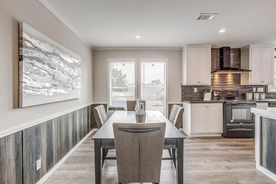 Dining space with light hardwood / wood-style flooring and ornamental molding