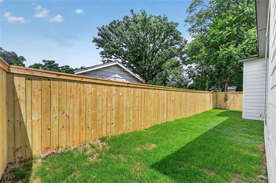 Private backyard featuring a new wood privacy fence, expansive green lawn, and exterior siding Private backyard featuring a new wood privacy fence, expansive green lawn, and exterior siding