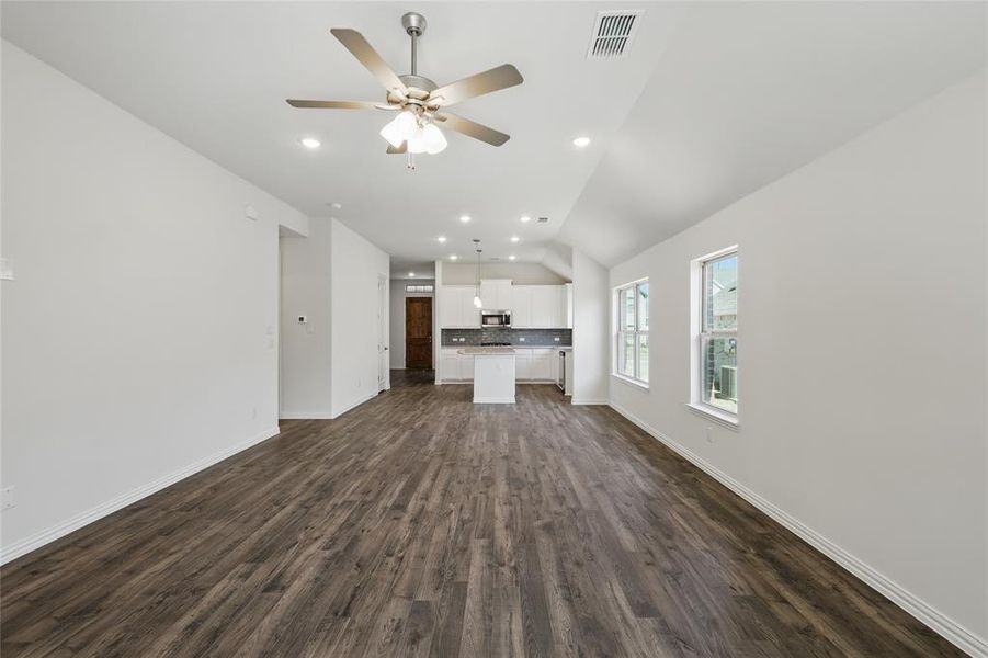 Unfurnished living room featuring recessed lighting, dark wood-style flooring, visible vents, and baseboards