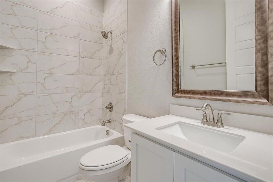 Full bathroom featuring toilet, vanity, and tiled shower / bath