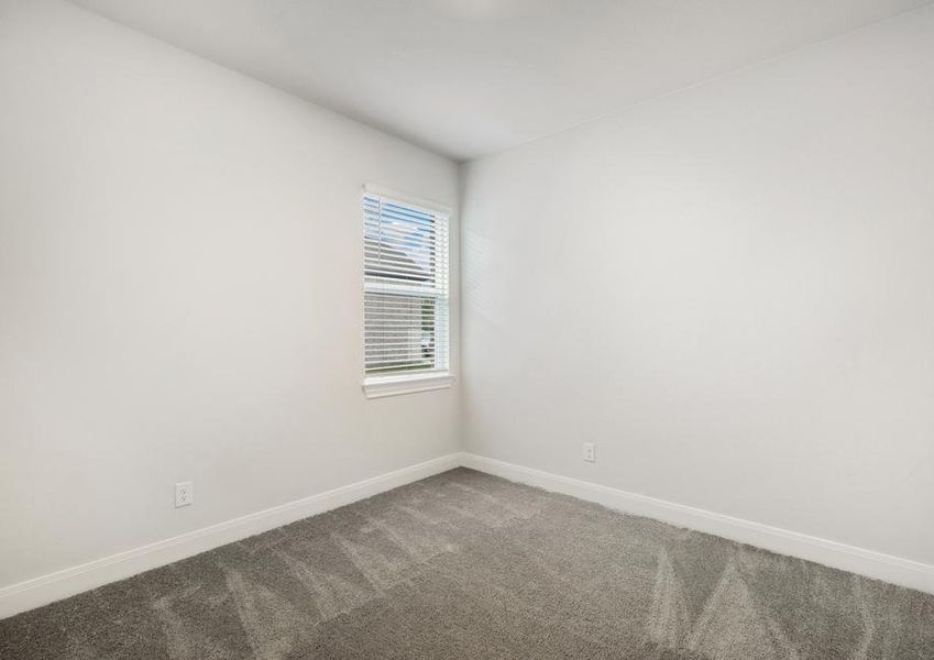 Secondary bedroom with tan carpet and a window.