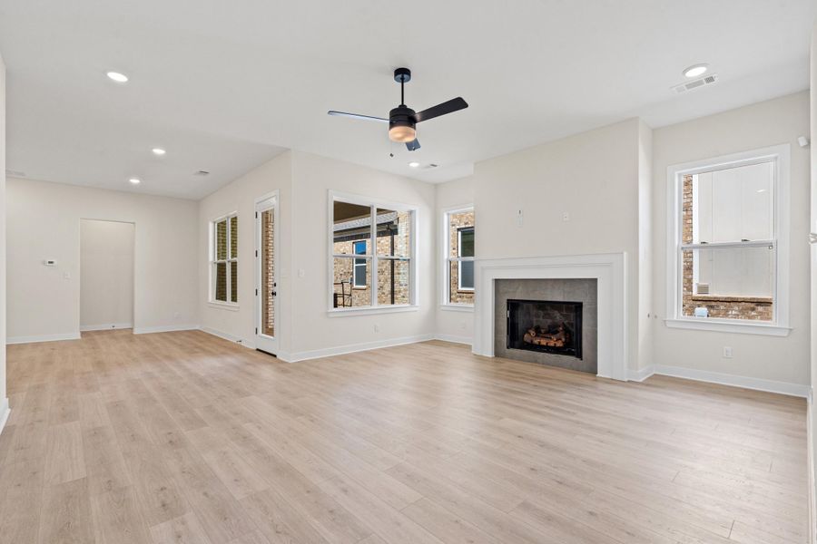 Unfurnished living room featuring ceiling fan, a fireplace, light wood-style flooring, and recessed lighting