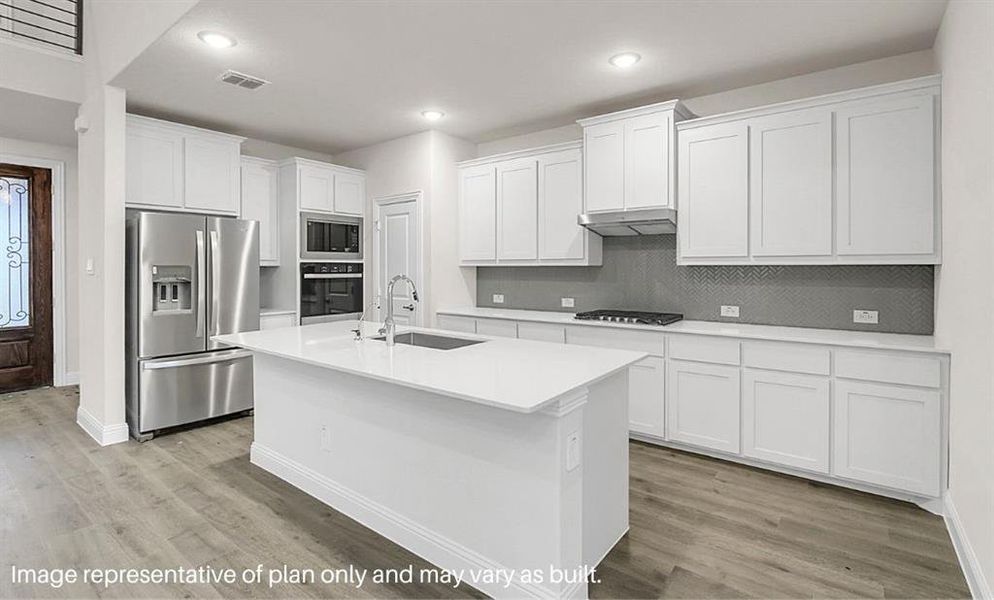 Kitchen featuring decorative backsplash, appliances with stainless steel finishes, sink, a center island with sink, and white cabinetry