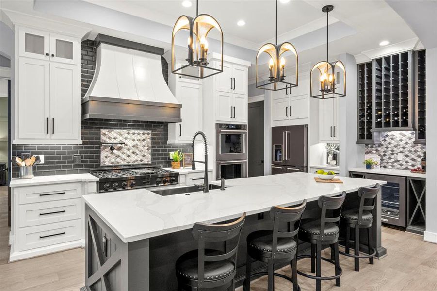 Chef's dream kitchen with double ovens, oversized island and farmhouse sink, ZLine range and pot filler under the large custom wood range hood with custom backsplash