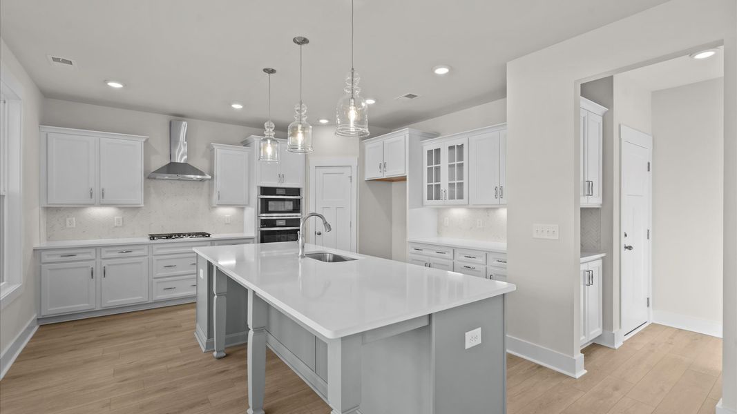 Tasteful design meets functional luxury in this kitchen with a 10-foot island and modern pendant lighting