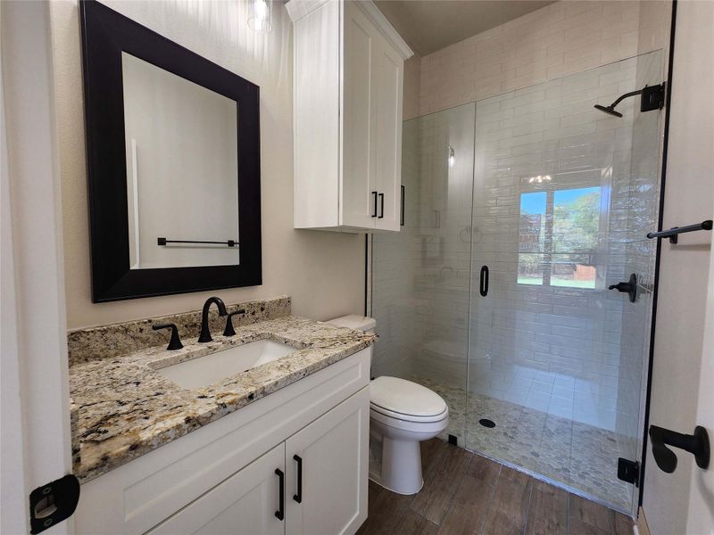 Full bath with vanity, a stall shower, and dark wood-style flooring