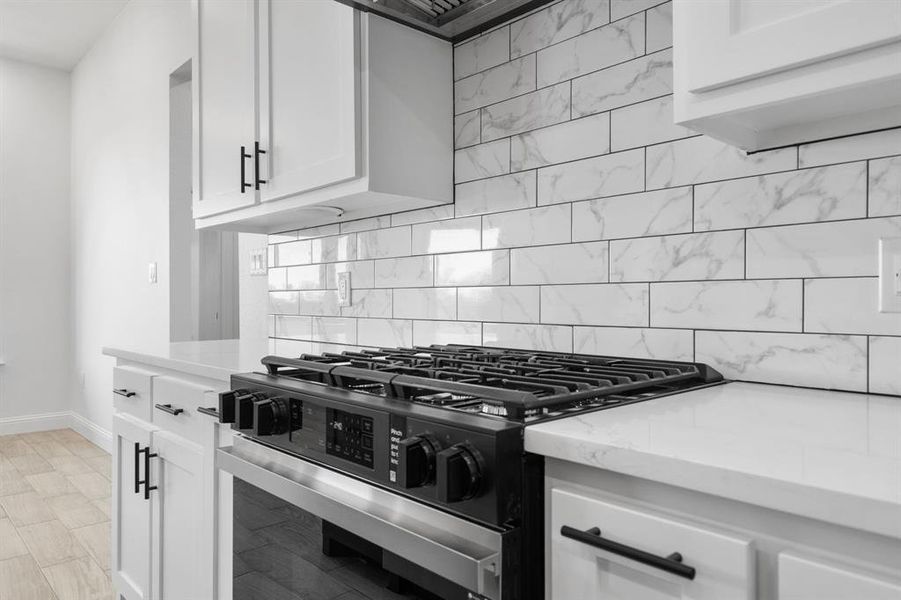 Kitchen featuring gas stove, white cabinets, and decorative backsplash