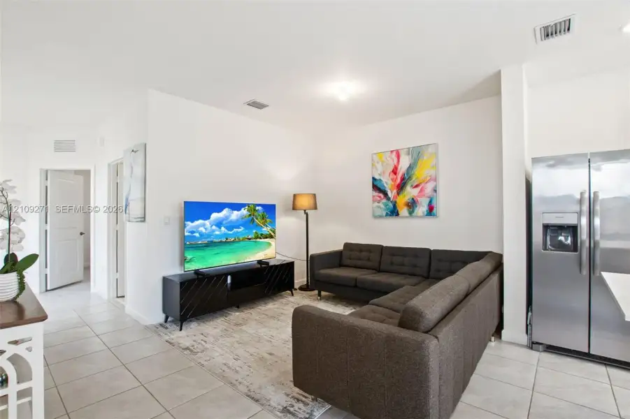 Neutral tile flooring and bright white walls featuring a stainless steel side-by-side refrigerator